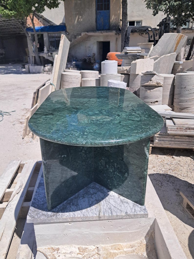 Puede incluir: Una mesa de m&aacute;rmol verde con una tapa rectangular redondeada y una base de pedestal. La mesa est&aacute; hecha de m&aacute;rmol verde pulido con vetas oscuras. La mesa mide aproximadamente 122 cm de largo y 61 cm de ancho.