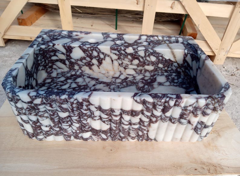 Puede incluir: Lavabo rectangular de m&aacute;rmol con base blanca y vetas moradas oscuras. El exterior presenta un dise&ntilde;o texturizado y acanalado. Este lavabo decorativo es adecuado para un ba&ntilde;o o aseo.