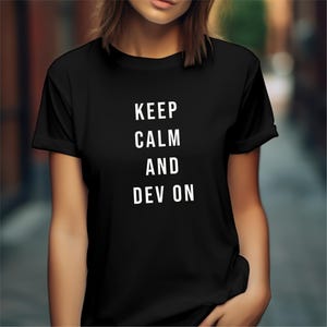 Può includere: T-shirt nero con la scritta bianca "KEEP CALM AND DEV ON". La maglietta ha maniche corte e girocollo. Il testo è centrato sulla parte anteriore della maglietta.