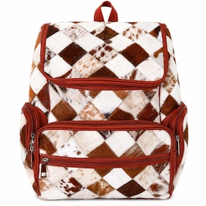 Puede incluir: Una mochila de patchwork marrón y blanco, con asa y ribetes rojos. La mochila presenta un patrón de diamantes y múltiples compartimentos con cremallera. El material parece ser texturizado, posiblemente cuero o una piel similar.