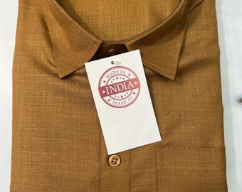 May include: A folded, mustard-colored button-down shirt with a chest pocket. The shirt has a brown collar and a tag that reads "MADE IN INDIA". The shirt is made of a textured fabric.