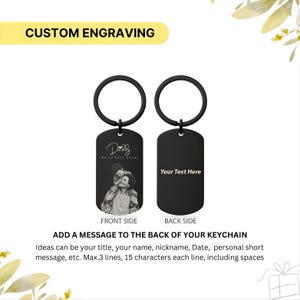 May include: A black metal dog tag keychain with a circular ring. The front side features an engraved photograph of a person carrying a child on their shoulders with the text Daddy World Best Daddy. The back side displays the text Your Text Here.