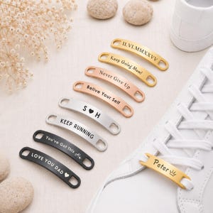 Puede incluir: Una colección de etiquetas metálicas curvas para cordones de zapatos en acabados dorado, oro rosa, plateado y negro. Cada etiqueta presenta grabados personalizados que incluyen nombres, fechas y frases motivadoras como Keep Going Mum y Never Give Up.
