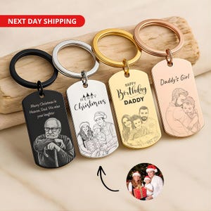 May include: Four rectangular metal keychains with split rings, featuring custom laser-engraved portraits and text. The keychains are black, silver, gold, and rose gold. Engravings include "Merry Christmas in Heaven, Dad," "Merry Christmas," "Happy Birthday DADDY," and "Daddy's Girl."