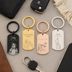 May include: Four rectangular metal keychains in black, gold, rose gold, and silver finishes. Each features a circular ring and is engraved with custom line-art portraits of people and text including "Daddy", "Love You Daddy", and "Drive Safe, Dad".