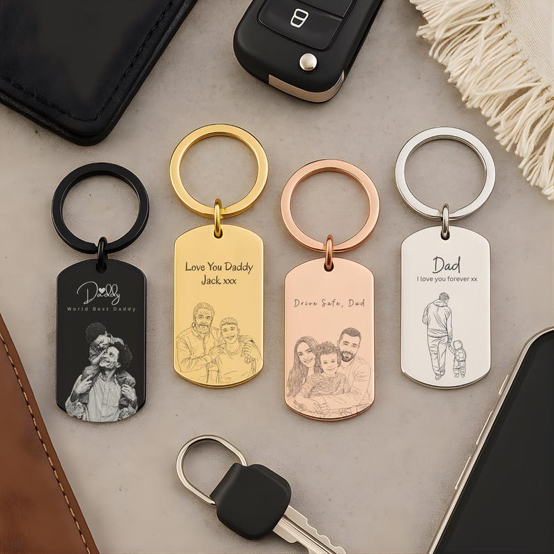 May include: Four rectangular metal keychains in black, gold, rose gold, and silver finishes. Each features a circular ring and is engraved with custom line-art portraits of people and text including "Daddy", "Love You Daddy", and "Drive Safe, Dad".