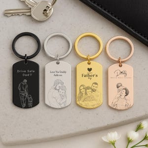 May include: Four rectangular metal keychains with split rings, featuring engraved line art illustrations and text. The keychains are black, silver, gold, and rose gold. The engravings include family portraits, figures, and phrases like Drive Safe Dad.
