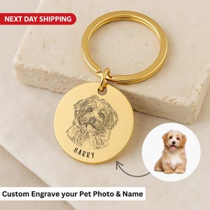 May include: A gold-coloured keyring with a circular pendant. The pendant has an engraved dog portrait and the name "HARRY". The text "Custom Engrave your Pet Photo & Name" is also visible.