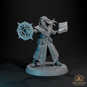 May include: A detailed miniature figure of a fantasy character, holding a shield with a geometric design and a book. The figure is wearing a long coat with intricate patterns and boots. The base has a cobblestone texture. The figure is a light blue color.