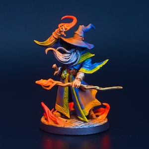May include: A miniature figurine of a wizard in a blue robe with yellow trim, a tall hat, and a long white beard. The wizard holds a wooden staff with orange flames. The base is dark gray.