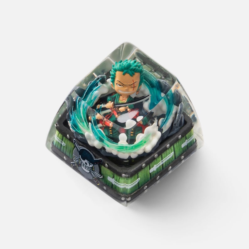 May include: A custom keycap featuring a miniature figure of Zoro from One Piece, surrounded by a swirling water effect. The keycap has a green and black base with a skull and crossbones emblem.