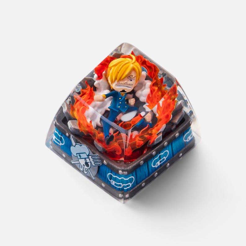 May include: A custom keycap featuring a character from the anime series One Piece. The keycap has a clear resin body with a detailed figure of Sanji surrounded by flames. The base is blue and gray with decorative elements.