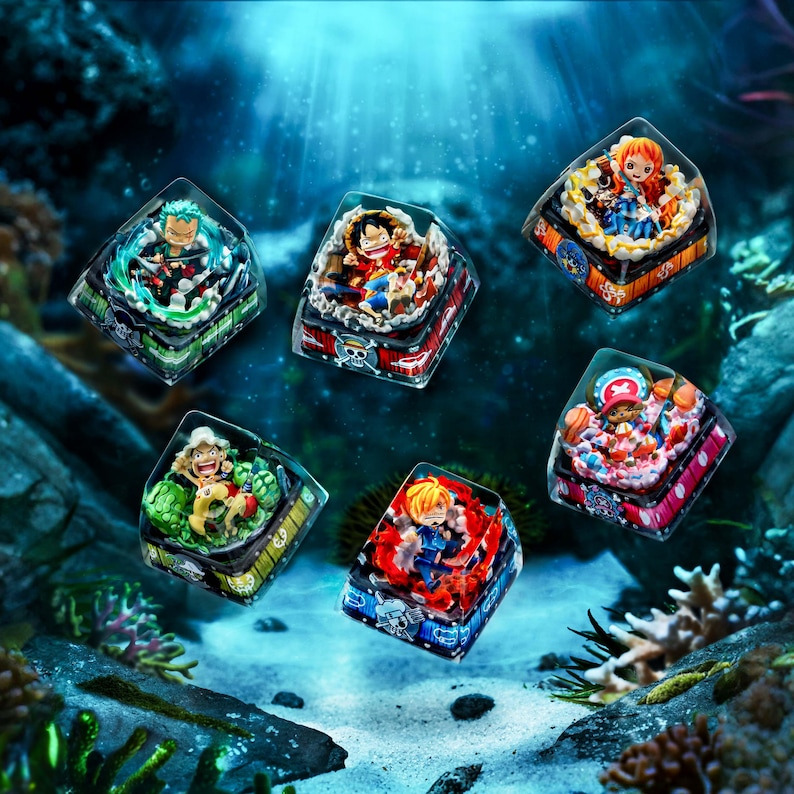 May include: Six colorful, square-shaped keycaps featuring anime characters. Each keycap has a clear top, showcasing detailed figures within a decorative base. The keycaps are set against a blurred underwater background with coral and aquatic plants.