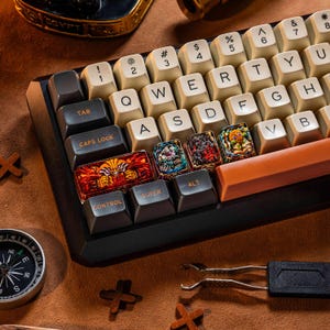 May include: A mechanical keyboard featuring a black frame, cream-colored alphanumeric keys, and dark gray modifier keys. Three custom artisan keycaps display detailed, colorful illustrations of fantasy characters, positioned above the control and alt keys.