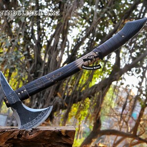 May include: A black and silver axe with a wooden handle. The handle is decorated with a pattern of stars and a symbol. The axe head has a curved blade and a sharp point. The axe is labelled "WindSlicer Axe" and "Damascus Maker".