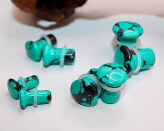 May include: A set of turquoise and black ear gauges with white silicone o-rings. The gauges are made of a natural stone with a marbled pattern.