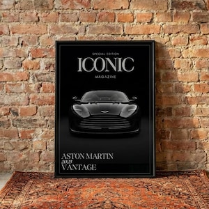 May include: A framed black and white magazine cover featuring a black Aston Martin car. The magazine is titled "ICONIC MAGAZINE" with the text "ASTON MARTIN 2025 VANTAGE" below the car. The image is set against a brick wall and a patterned rug.