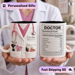 Può includere: Una tazza in ceramica bianca con una grafica in rilievo di un camice da medico, uno stetoscopio rosa, strumenti medici e un cartellino con il nome Dr. Elara. Il retro mostra un'etichetta con i valori nutrizionali per un medico.