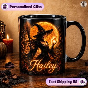 May include: A black ceramic mug featuring a graphic of a witch in a pointed hat holding a broom and a glowing orb against a large orange full moon. The name Hailey is written in a glowing orange script font at the bottom of the illustration.