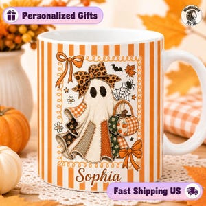 May include: A white ceramic mug featuring vertical orange and white stripes. The center graphic displays a ghost wearing a leopard print bow, holding a pumpkin basket, surrounded by autumn leaves, a spider web, and the name Sophia in script.