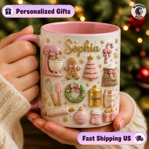 May include: A white ceramic mug with a pink interior and handle, featuring raised 3D-style holiday baking icons including a pink stand mixer, gingerbread person, Christmas tree, wreath, rolling pin, and gift box, with the name Sophia in gold script.