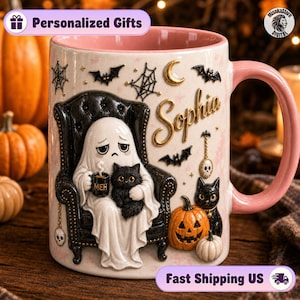 May include: A ceramic mug with a pink interior and handle, featuring a ghost sitting in a black tufted chair holding a mug labeled MEH and a black cat. The design includes the name Sophia, bats, spiderwebs, a crescent moon, and pumpkins.