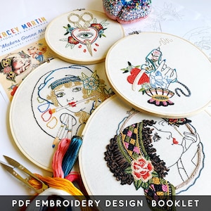 May include: A collection of embroidered hoop art with tattoo-inspired designs. The designs include scissors, hearts, and portraits, with colorful thread on a cream background. The text "PDF EMBROIDERY DESIGN BOOKLET" is at the bottom.