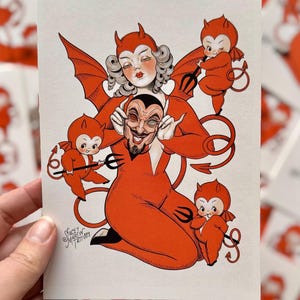 May include: A vintage-style illustration featuring a red devil figure with a smiling face, surrounded by three small devil figures. The central figure has red horns, wings, and a trident. The artwork is signed "Stacey Martin Tattoos".