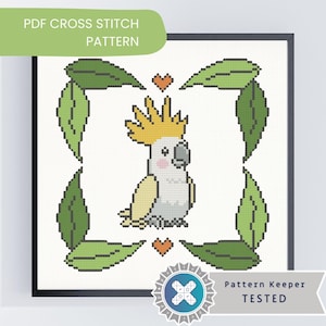 May include: A framed cross-stitch design of a cockatoo with yellow crest and white body, framed by green leaves and orange hearts. The text "PDF CROSS STITCH PATTERN" is at the top, and "Pattern Keeper TESTED" is at the bottom.