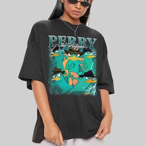 May include: Black t-shirt with a graphic of Perry the Platypus from the animated series. The design shows cartoon platypuses in fedoras, with the text "PERRY the Platypus". The shirt has a vintage, distressed appearance.