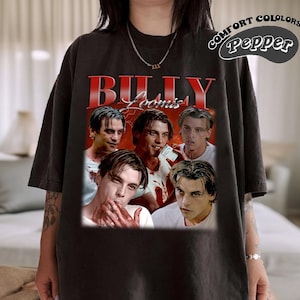 May include: Dark gray t-shirt featuring a graphic of Billy Loomis from the movie Scream. The graphic includes multiple images of the character and the text "Billy Loomis" in red. The shirt also has the text "Comfort Colors Pepper" in a circular design.