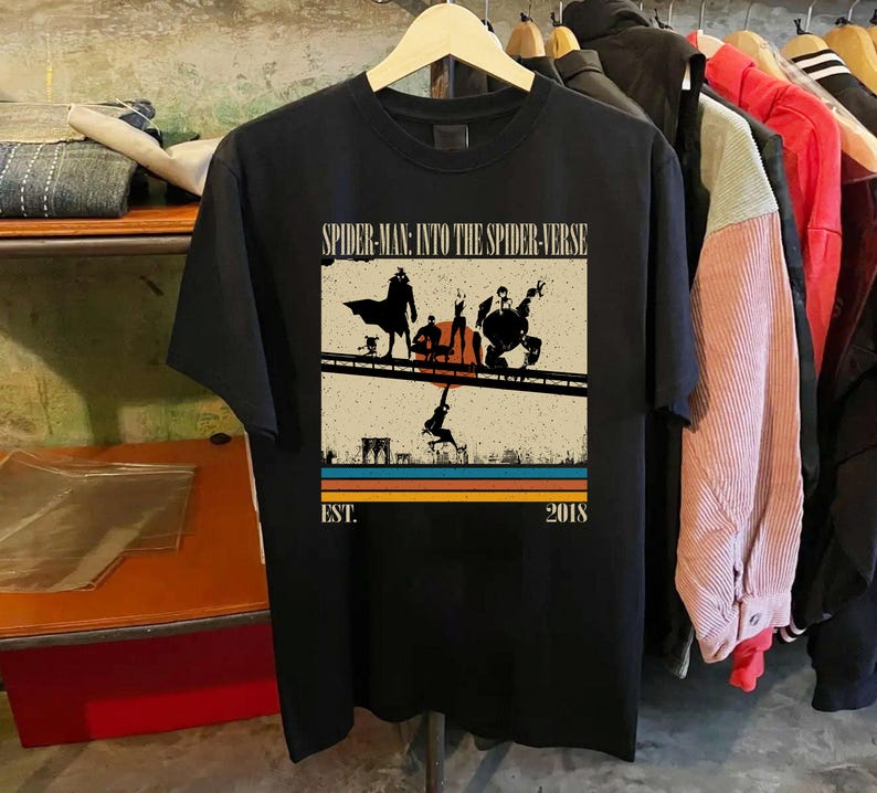Puede incluir: Camiseta negra con un gr&aacute;fico de la pel&iacute;cula "Spider-Man: Into the Spider-Verse". El dise&ntilde;o incluye siluetas de personajes en un puente, con el texto "SPIDER-MAN: INTO THE SPIDER-VERSE" y "EST. 2018."