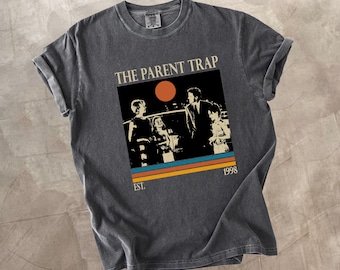 May include: Dark grey t-shirt featuring a graphic from "The Parent Trap" movie. The design includes a retro image of the characters, a sunset, and the text "THE PARENT TRAP" and "1998". The shirt has rolled-up sleeves.