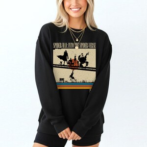 Puede incluir: Sudadera negra con un dise&ntilde;o retro de la pel&iacute;cula "Spider-Man: Into the Spider-Verse". El dise&ntilde;o muestra siluetas de personajes de Spider-Man y el t&iacute;tulo de la pel&iacute;cula. La sudadera tiene mangas largas y cuello redondo.