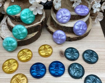 May include: Assortment of 15 resin moon face buttons in various colors, including gold, teal, purple, blue, and green. The buttons feature a raised, detailed face design.