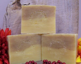 May include: Three bars of handmade soap with a brown and yellow swirl design. The soap is labeled "Cedar Creek Soaps" and "Handcrafted Soaps".