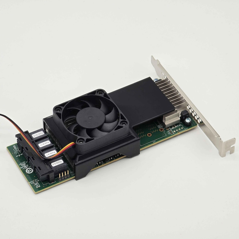 May include: A computer component featuring a green circuit board with a black fan and heat sink. The fan is centered on a black housing, and a metal bracket extends from the board. Several connectors are visible.