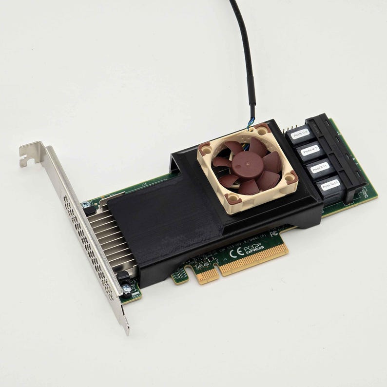 Pu&ograve; includere: Una scheda di espansione PCI Express verde con un dissipatore di calore nero e una piccola ventola color marrone e beige. La scheda include una staffa di montaggio in metallo argentato e quattro porte nere etichettate Ports 0-3, 4-7, 8-11 e 12-15.