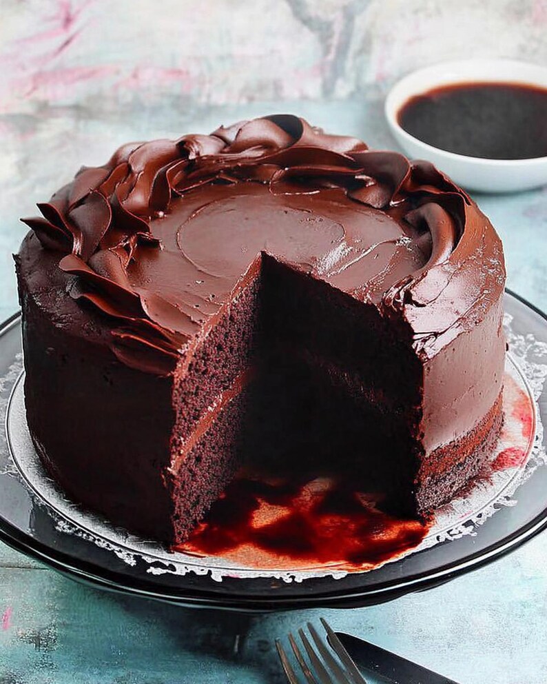 May include: A chocolate cake with a slice removed, revealing the dark, moist layers. The cake is covered in rich chocolate frosting, with decorative swirls on top. It sits on a clear plate with a white doily.