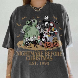 Puede incluir: Camiseta gris oscuro con un gr&aacute;fico de "Pesadilla antes de Navidad" con Jack Skellington, Sally y otros personajes. El texto "NIGHTMARE BEFORE CHRISTMAS EST. 1993" est&aacute; impreso debajo. La camiseta tiene una etiqueta Comfort Colors Pepper.
