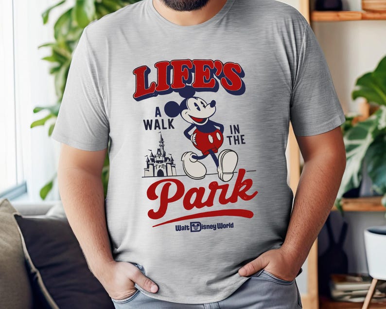 Puede incluir: Camiseta gris claro con Mickey Mouse y el texto "LIFE'S A WALK IN THE PARK" en rojo y azul. El dise&ntilde;o incluye un castillo y las palabras "Walt Disney World" en blanco.