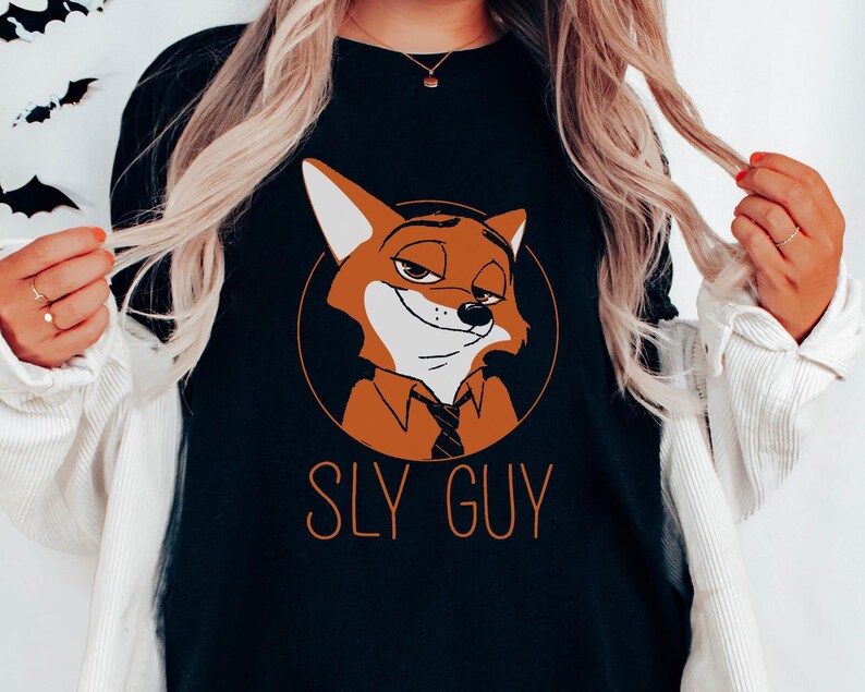 Puede incluir: Camiseta negra de cuello redondo con un personaje de zorro de dibujos animados en un c&iacute;rculo naranja. El zorro tiene una expresi&oacute;n astuta y lleva una corbata. El texto "SLY GUY" est&aacute; impreso debajo del zorro en naranja.