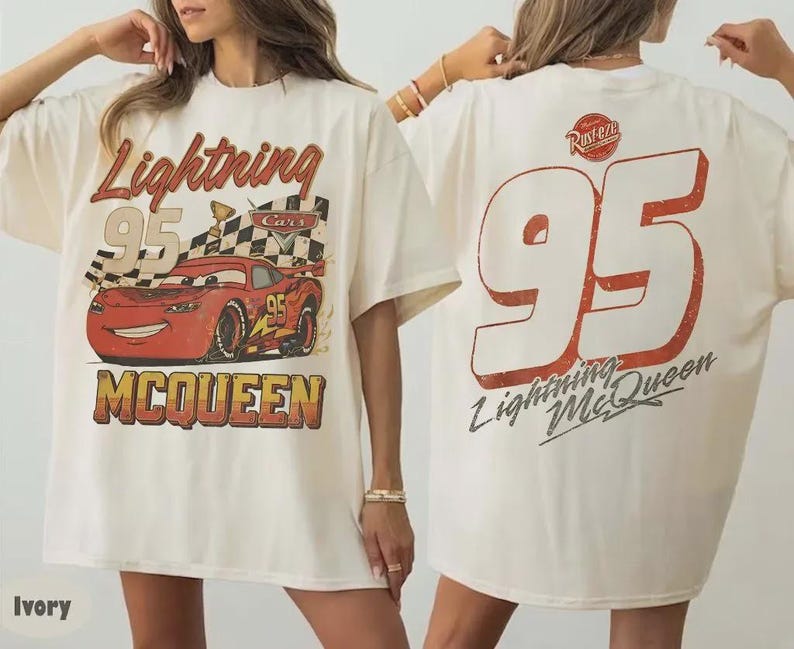 Op de afbeelding: Ivoor kleurig T-shirt met een Lightning McQueen-afbeelding uit de film Cars. De voorkant toont "Lightning 95 McQueen" met een geblokte vlag en een rode raceauto. De achterkant heeft een grote "95" en "Lightning McQueen".