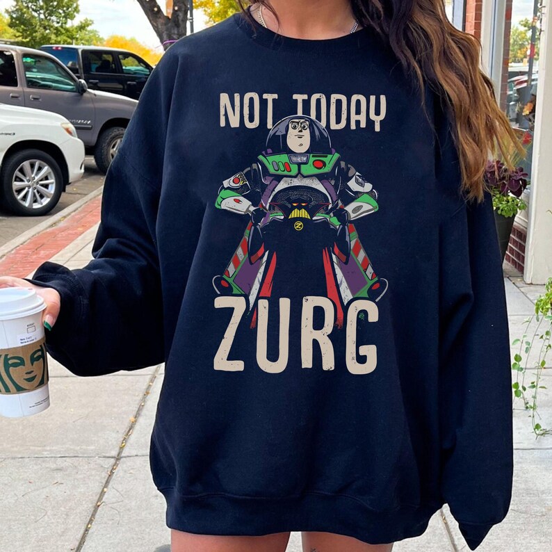 Op de afbeelding: Marineblauwe sweatshirt met een Zurg-afbeelding uit Toy Story en de tekst "NOT TODAY ZURG". Het Zurg-ontwerp is in groen, paars en zwart. Een casual, comfortabele top.
