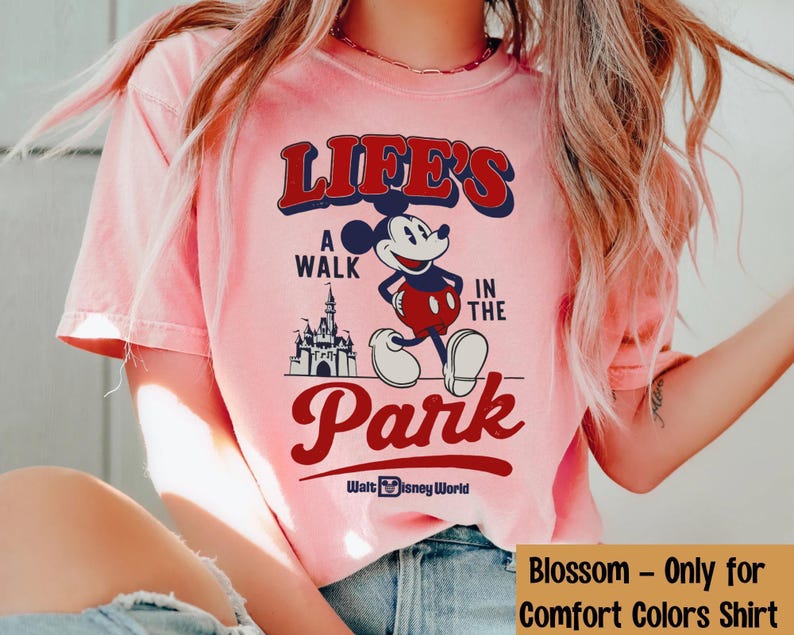 Puede incluir: Camiseta rosa claro con Mickey Mouse y el texto "LIFE'S A WALK IN THE PARK" en rojo y azul marino. El dise&ntilde;o incluye un castillo y "Walt Disney World".