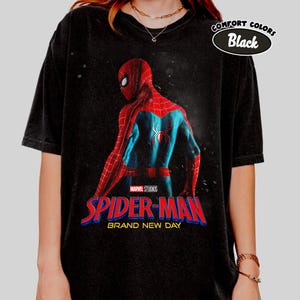 May include: Black t-shirt with a graphic of Spider-Man in a red and blue suit, and the text "SPIDER-MAN BRAND NEW DAY" in red and blue. The shirt has a "Comfort Colors Black" label.
