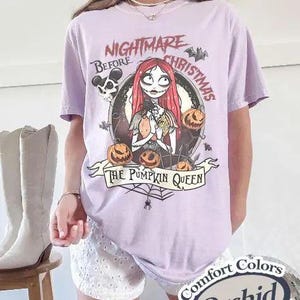 May include: A light purple short-sleeve t-shirt featuring a graphic of Sally from The Nightmare Before Christmas surrounded by pumpkins, bats, and a spider web. The text reads Nightmare Before Christmas and The Pumpkin Queen.