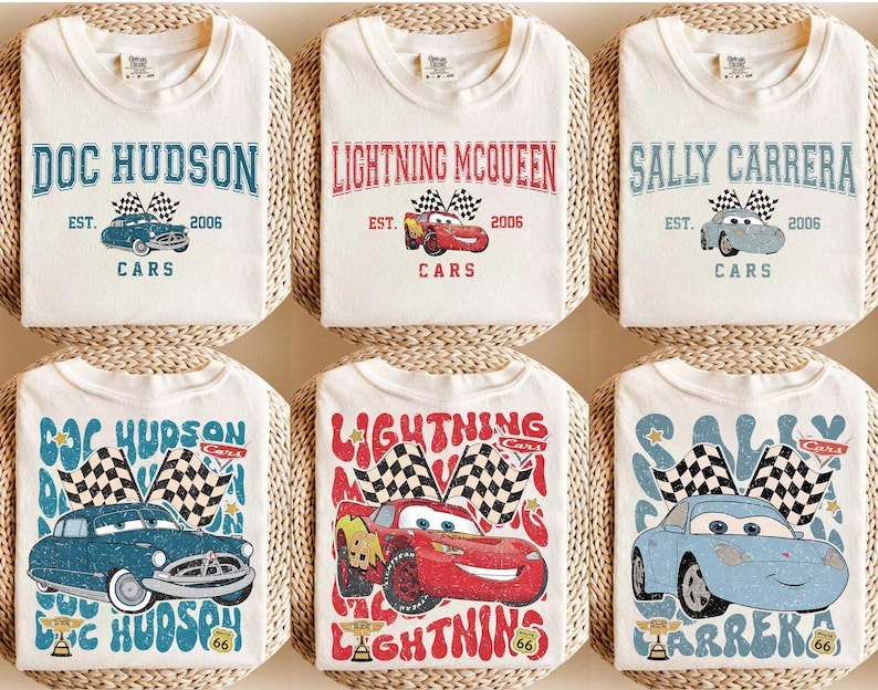 May include: Six white t-shirts featuring designs from the movie Cars. Each shirt displays a different character's name: Doc Hudson, Lightning McQueen, and Sally Carrera. The designs include the character's image, the year 2006, and the word "Cars".