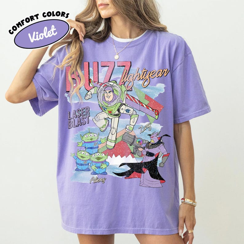 Puede incluir: Camiseta violeta Comfort Colors con un gr&aacute;fico de Buzz Lightyear, extraterrestres y Zurg de Toy Story. El dise&ntilde;o incluye el texto "Buzz Lightyear" y "Laser Blast". La camiseta tiene un corte relajado.