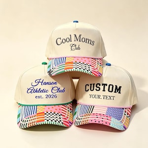 May include: Three cream-colored baseball caps with multicolored patchwork brims. The top cap features embroidered text reading Cool Moms Club. The bottom left cap reads Hanson Athletic Club est. 2026. The bottom right cap reads CUSTOM YOUR. TEXT.